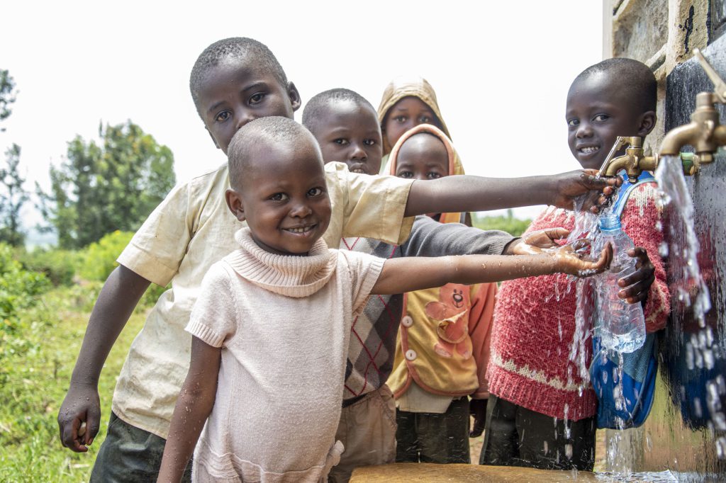 Kinderen in Tamu staan bij waterpomp